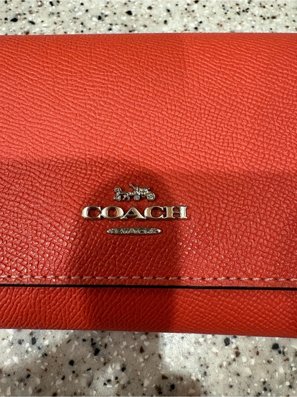Coach Slim Trifold Wallet in a vibrant coral or orange color